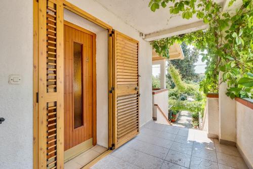 an open wooden door on a house with a porch at House ROSSELLA with cozy apartment and rooms close to the beach in Nerezine