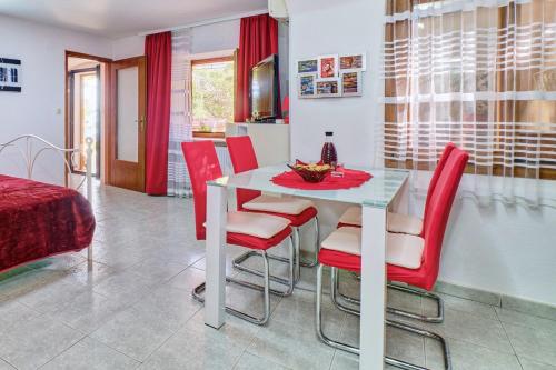 a dining room with a white table and red chairs at House ROSSELLA with cozy apartment and rooms close to the beach in Nerezine