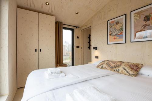 een groot wit bed in een kamer met een raam bij Hello Zeeland - Tiny House Zeeuwse Liefde 11 in Westkapelle