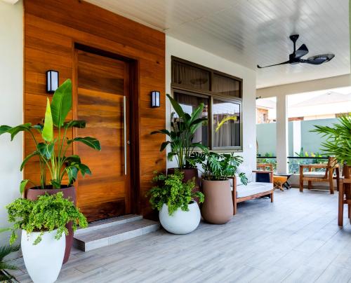 a porch with potted plants and a wooden door at Château NaNa Willine in Accra