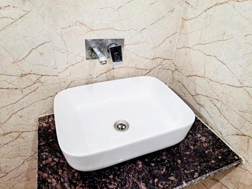 a white sink in a bathroom with a marble wall at Hotel Maharaja - Majnu-ka-tilla in New Delhi