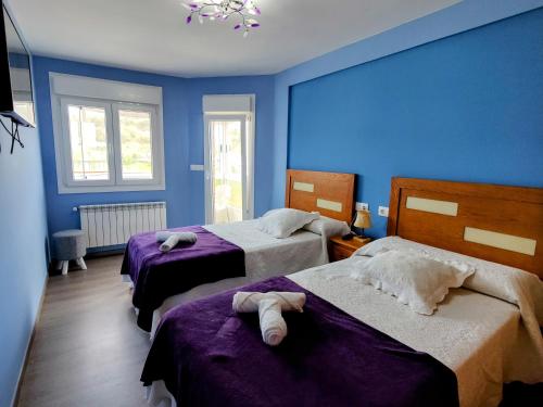 - une chambre avec 2 lits et des murs bleus dans l'établissement López Estación, à Sarria