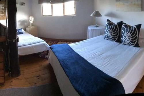 1 dormitorio con 2 camas y almohadas azules y blancas en Cheerful 10 sleeper cottage - Shower with a view. en Lusikisiki