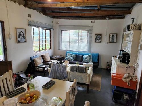 uma sala de estar com um sofá e uma mesa em Cheerful 10 sleeper cottage - Shower with a view. em Lusikisiki