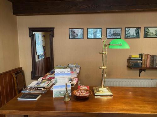 a desk with a green lamp and books on it at Hotel garni Am Dippeplatz in Quedlinburg