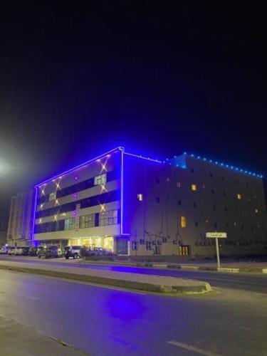 un edificio con luces púrpuras en el lateral. en فنون راحتي للشقق المخدومة, en Shariyah