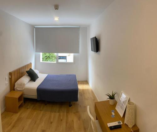 a bedroom with a bed and a window and a table at Nanit Valencia Hostel in Valencia