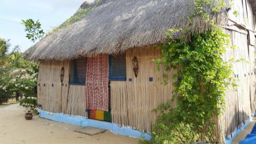 a house with a thatch roof and a window at A&Y Wild Camp Ghana in Keta