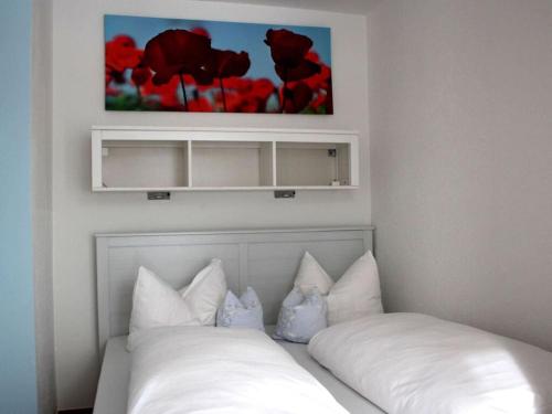 1 cama con almohadas blancas y una pintura en la pared en Holiday apartment Sonia on the lake, en Bad Wiessee