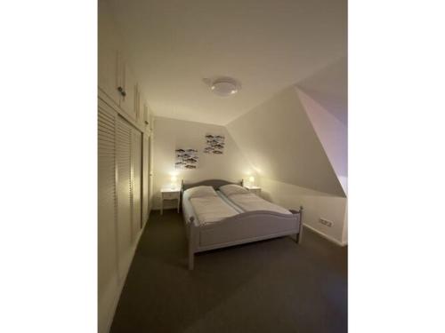 a bedroom with a white bed in a attic at Holiday apartment Möwennest in Lindholm