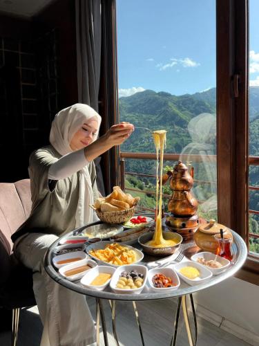 a woman sitting at a table with a tray of food at Peruma otel bungalov in Çamlıhemşin