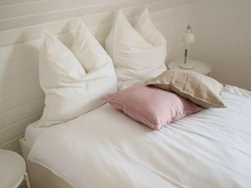 een bed met witte kussens en een roze kussen bij Holiday home Eifel H time out in Monschau