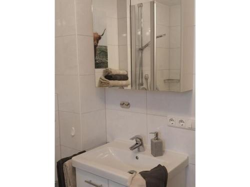 a white bathroom with a sink and a mirror at Holiday apartment Edelweiss in Rieden am Forggensee