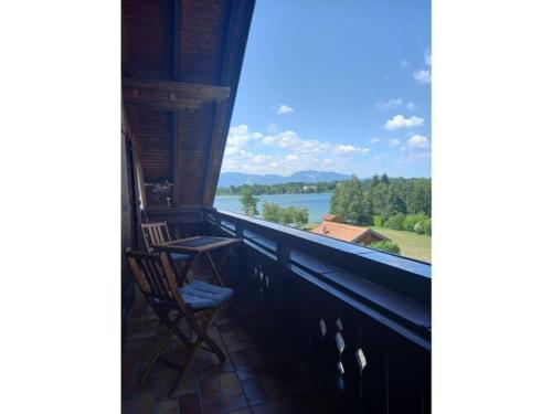 a balcony with a chair and a view of a lake at Holiday apartment Bräu in Riegsee