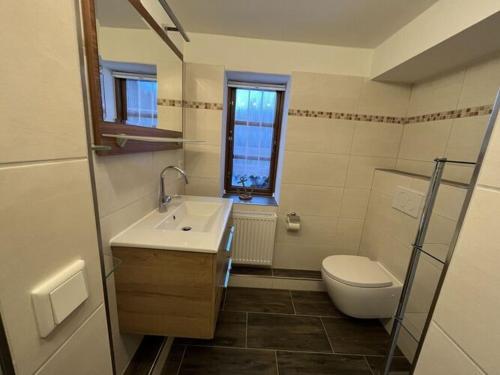 een badkamer met een wastafel, een toilet en een raam bij Holiday apartment Ebbe in Stedesand