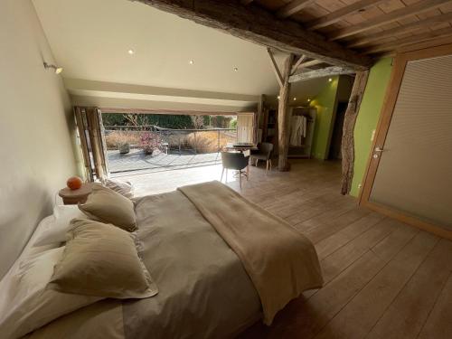 ein großes Bett in einem Zimmer mit einem großen Fenster in der Unterkunft Le Temps d'une Pause in Ny