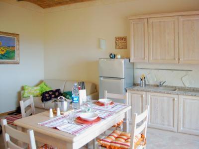 a kitchen with a table with chairs and a refrigerator at Una Finestra sul Silenzio Monolocale in Santa Luce