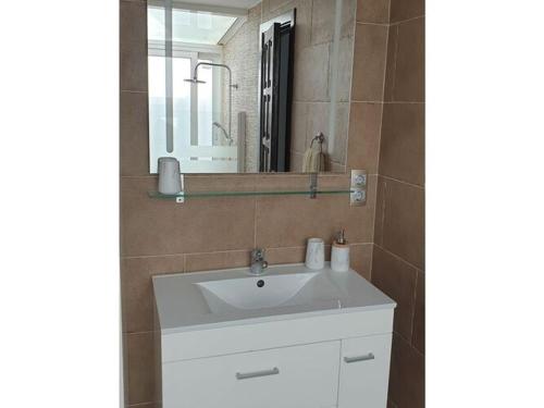 ein Badezimmer mit einem weißen Waschbecken und einem Spiegel in der Unterkunft Bungalow Villa del Sol in Morro del Jable