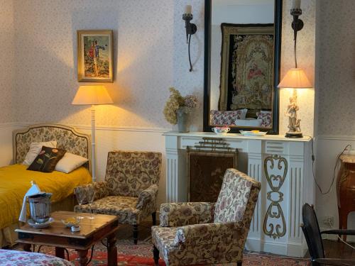 a living room with a bed and two chairs at Maison d'Hôtes de l'Ancien Couvent des Carmes in Mortemart