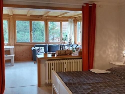 a bedroom with a bed and a living room with windows at Holiday apartment Alpenrose in Rieden am Forggensee