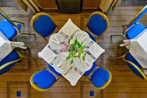 a table with plates and flowers on it with blue chairs at BEST BALTIC Hotel Druskininkai Central in Druskininkai