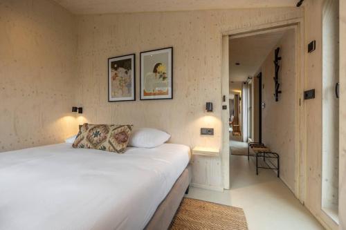 1 dormitorio con 1 cama blanca grande y pasillo en Hello Zeeland - Tiny House Zeeuwse Liefde 12 en Westkapelle