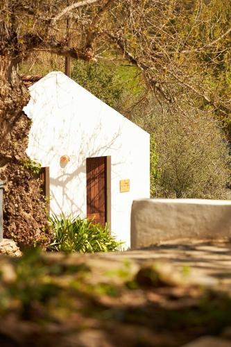 a white building with a door in a yard at Quinta Do Marmeleiro - Casa Rosmaninho in Santiago do Cacém