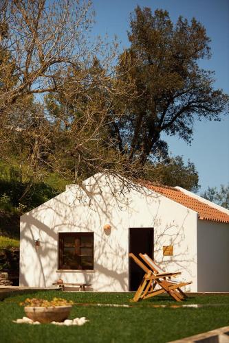 a small white building with two wooden lounges in front of it at Quinta Do Marmeleiro - Casa Rosmaninho in Santiago do Cacém