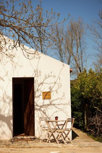 a white building with a door and two chairs at Quinta Do Marmeleiro - Casa Rosmaninho in Santiago do Cacém