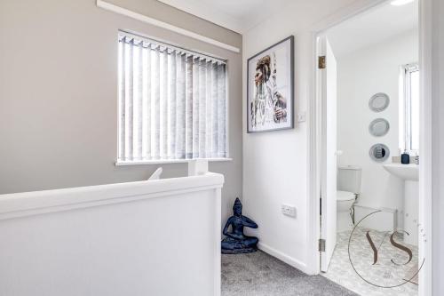 a white bathroom with a window and a toilet at Modern 3BR Home in 9 Anson Rd Near Sandwell Hospital with Garden and Free Parking in West Bromwich