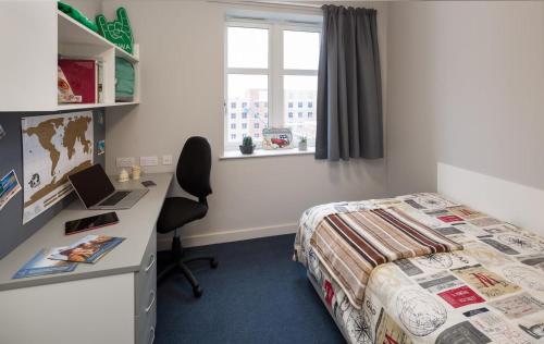 um quarto com uma secretária, uma cama e uma janela em Ensuite Bedrooms with Shared Kitchen at Bay Campus located in Swansea em Swansea