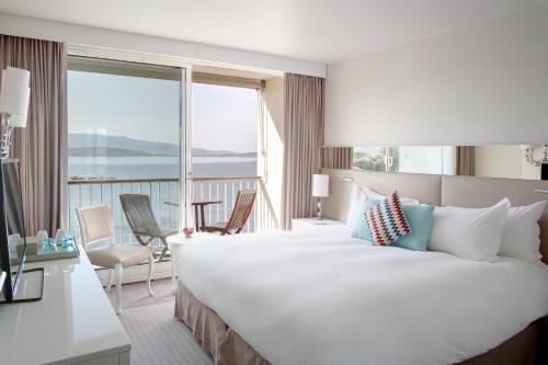 a hotel room with a large bed and a balcony at Sofitel Golfe d'Ajaccio Thalassa Sea & Spa in Ajaccio