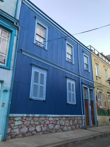 a blue building with white windows on a street at B&B La Nona in Valparaíso