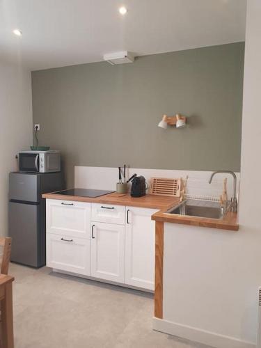 une cuisine avec des armoires blanches, un évier et un réfrigérateur dans l'établissement Appartement central, à Nyons