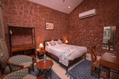 a bedroom with a bed and a stone wall at Impian Resorts in Jodhpur