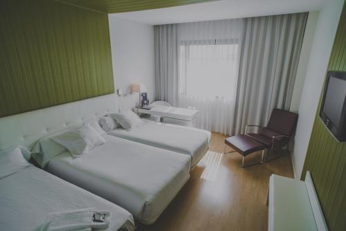 a hotel room with two beds and a chair at Hotel Zentral Castellana Norte in Madrid