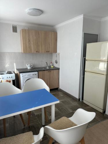 eine Küche mit einem blauen Tisch und Stühlen sowie einem Kühlschrank in der Unterkunft Квартира in Priozersk