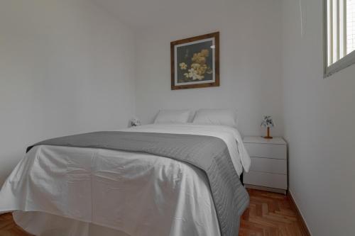um quarto branco com uma cama e uma fotografia na parede em Apartamento Próximo Avenida Paulista, Sirio e FGV em São Paulo