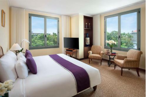 a hotel room with a large bed and windows at Avani Hai Phong Harbour View Hotel in Hai Phong