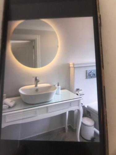 a white bathroom with a sink and a mirror at Aşiyan Yalısı in İznik