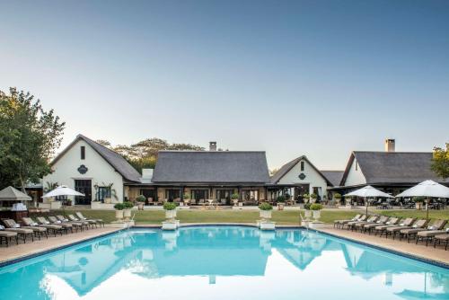un hôtel avec une piscine, des chaises et un bâtiment dans l'établissement Royal Livingstone Hotel by Anantara, à Livingstone