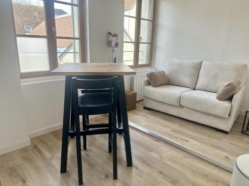 a table and chair in a living room with a couch at L'Appart des Platanes in Romorantin