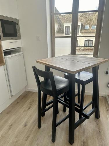 a wooden table and chairs in a kitchen with a window at L'Appart des Platanes in Romorantin