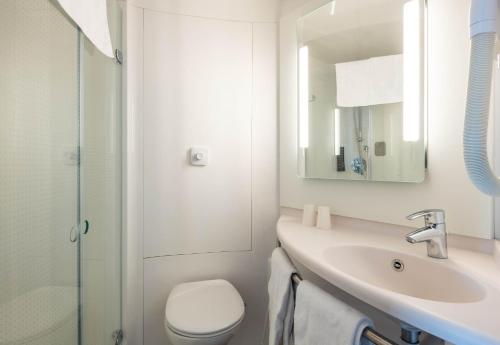 a white bathroom with a toilet and a sink at B&B HOTEL Calais Terminal Cité Europe 3 étoiles in Coquelles
