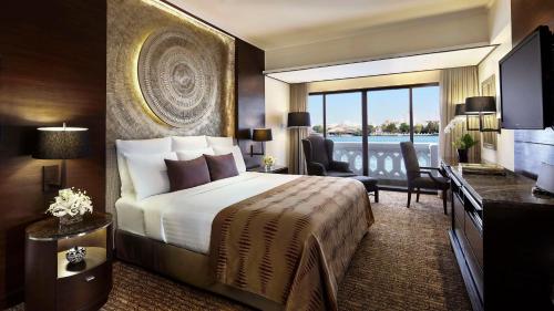 a hotel room with a bed and a large window at Anantara Riverside Bangkok Resort in Bangkok