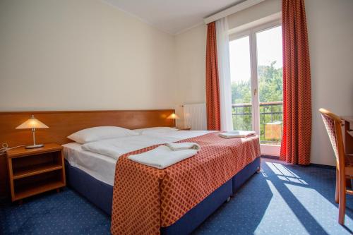 um quarto de hotel com uma cama e uma janela em Főnix Hotel em Balatonföldvár