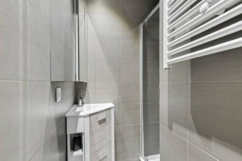 une salle de bain blanche avec une douche et un lavabo dans l'établissement Charmant appartement entier à Montmartre pour 4, à Paris