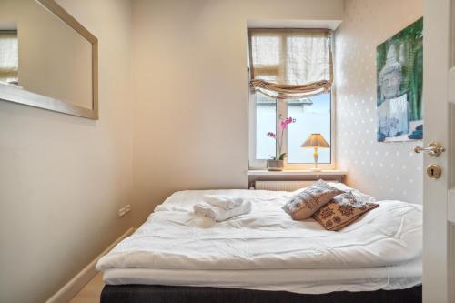 Schlafzimmer mit einem weißen Bett und einem Fenster in der Unterkunft Luksuriøst 3BR Strandhus m.plads til 6 personer in Hellerup