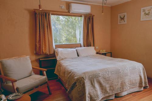 a bedroom with a bed and a chair and a window at Equs Posada de Campo in San Carlos de Bariloche