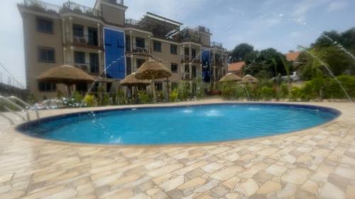 a blue swimming pool in front of a building at Kitiko residence Hotel in Entebbe